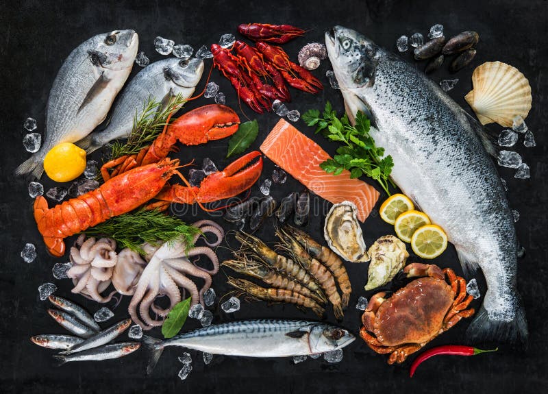 Fresh fish and seafood arrangement on black stone background. Fresh fish and seafood arrangement on black stone background