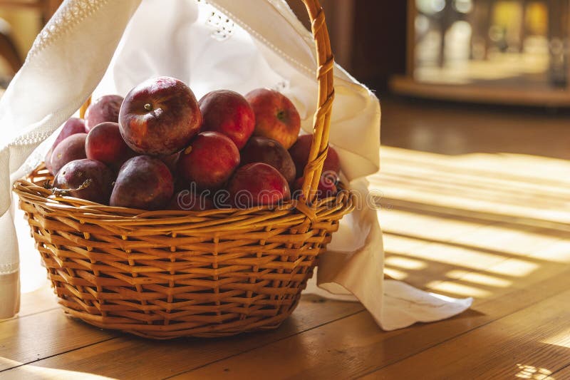 Φρέσκα κόκκινα μήλα σε ένα λυγερό καλάθι με λευκό πανί με ζεστό ηλιακό φως, η συγκομιδή του φθινοπώρου είναι ζωντανή στοκ εικόνες