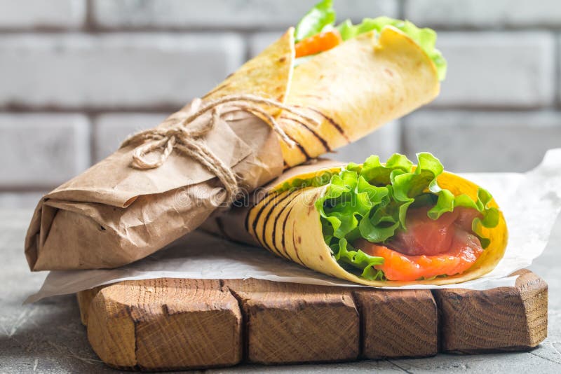 fresh tortilla wrap with vegetables and salmon on paper. fresh tortilla wrap with vegetables and salmon on paper
