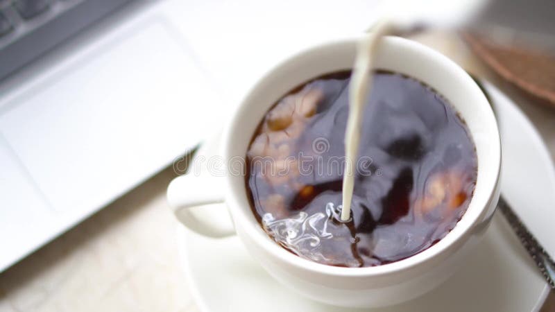 Φρέσκο γάλα που χύνεται σε ένα φλιτζάνι καφέ