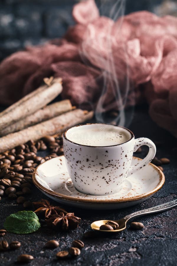 White cup of fresh tasty hot coffee espresso with coffee beans on dark background. White cup of fresh tasty hot coffee espresso with coffee beans on dark background