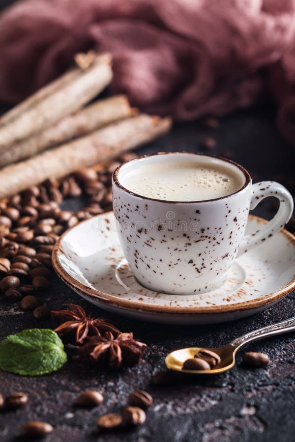 White cup of fresh tasty hot coffee espresso with coffee beans on dark background. White cup of fresh tasty hot coffee espresso with coffee beans on dark background