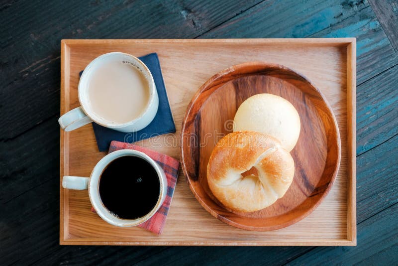 Φρέσκο σπιτικό Bagel ψωμί και καυτός καφές, τσάι γάλακτος στον ξύλινο δίσκο στοκ φωτογραφίες