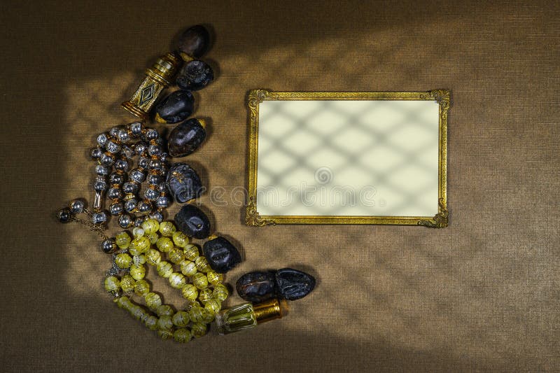 Date fruits and rosary muslim and Oud perfume arranged in moon shape and empty gold frame, shadow window. Islamic festive food and it's significance. Date fruits and rosary muslim and Oud perfume arranged in moon shape and empty gold frame, shadow window. Islamic festive food and it's significance