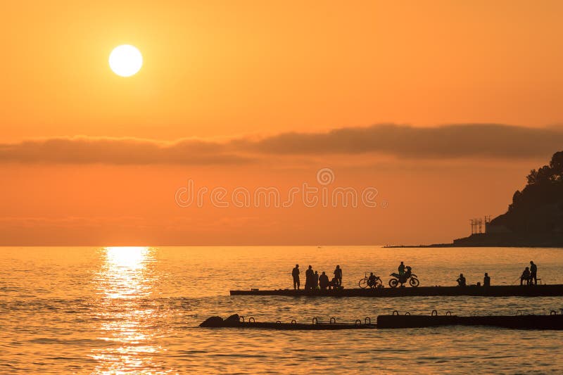 Φυσικό seascape ηλιοβασιλέματος θάλασσας με τις απόμακρες σκιαγραφίες των ανθρώπων στοκ φωτογραφίες με δικαίωμα ελεύθερης χρήσης Φυσικό seascape ηλιοβασιλέματος θάλασσας με τις απόμακρες σκιαγραφίες των ανθρώπων στοκ φωτογραφίες με δικαίωμα ελεύθερης χρήσης