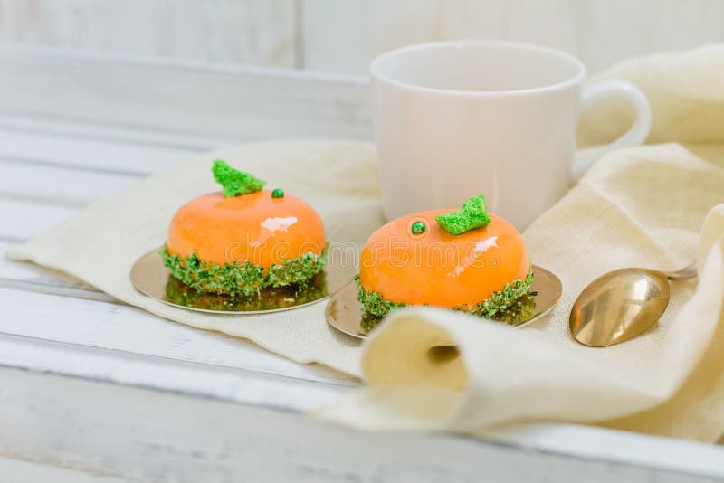 Φωτεινά πορτοκαλιά mousse κέικ και φλιτζάνι του καφέ στον άσπρο ξύλινο δίσκο στοκ εικόνες Φωτεινά πορτοκαλιά mousse κέικ και φλιτζάνι του καφέ στον άσπρο ξύλινο δίσκο στοκ εικόνες