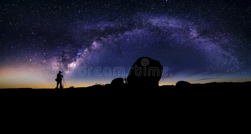 Photographer doing astro photography in a desert nightscape with milky way galaxy. The background is stary celestial bodies in astronomy. The heaven depicts science and the divine. Photographer doing astro photography in a desert nightscape with milky way galaxy. The background is stary celestial bodies in astronomy. The heaven depicts science and the divine.
