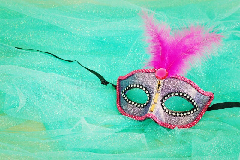 Photo of elegant and delicate pink and purple Venetian mask over mint chiffon background. Photo of elegant and delicate pink and purple Venetian mask over mint chiffon background.