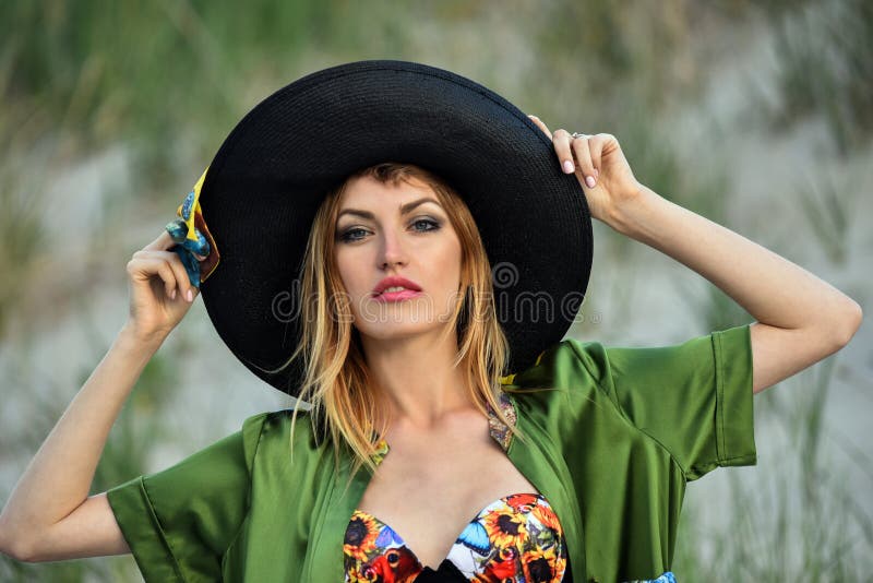 Φωτογραφία μιας όμορφης νέας γυναίκας σε ένα καπέλο και του μαγιό στην παραλία στοκ εικόνα με δικαίωμα ελεύθερης χρήσης Φωτογραφία μιας όμορφης νέας γυναίκας σε ένα καπέλο και του μαγιό στην παραλία στοκ εικόνα με δικαίωμα ελεύθερης χρήσης