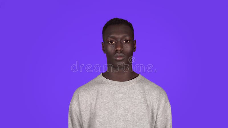 φωτογραφία πρόσοψης ενός νεαρού σοβαρού ήρεμου άνδρα που κοιτάζει την κάμερα. όμορφος αφρικανός μαύρος άνδρας με λευκή μπλούζα