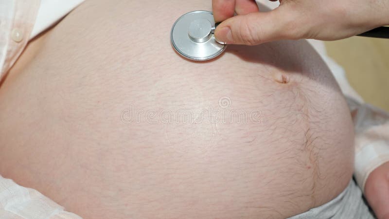 χέρι αγνώστου άνδρα οδηγεί ένα στηθοσκόπιο πάνω από τη μεγάλη κοιλιά μιας εγκύου φιλμ μικρού μήκους
