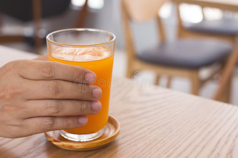 Χέρι ατόμων που κρατά ένα ποτήρι του χυμού από πορτοκάλι στοκ φωτογραφίες Χέρι ατόμων που κρατά ένα ποτήρι του χυμού από πορτοκάλι στοκ φωτογραφίες