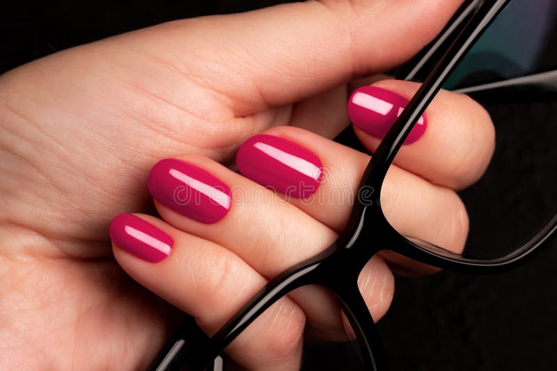 χέρι με viva magenta ροζ καρφιά και γυαλιά στοκ εικόνες