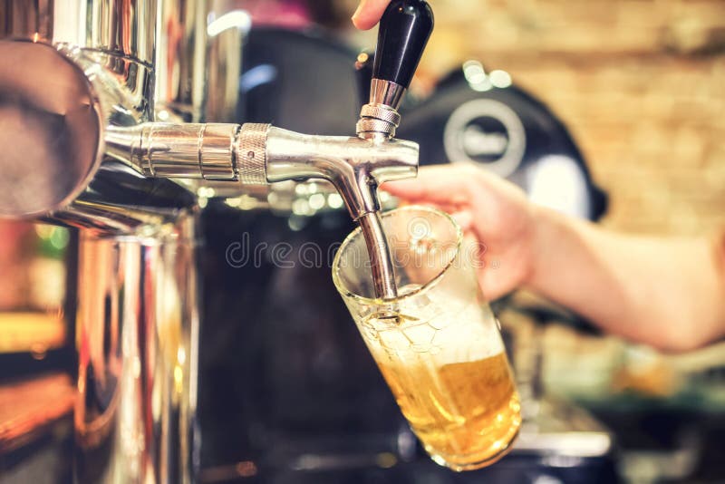 Barman hand at beer tap pouring a draught lager beer serving in a restaurant or pub. Barman hand at beer tap pouring a draught lager beer serving in a restaurant or pub