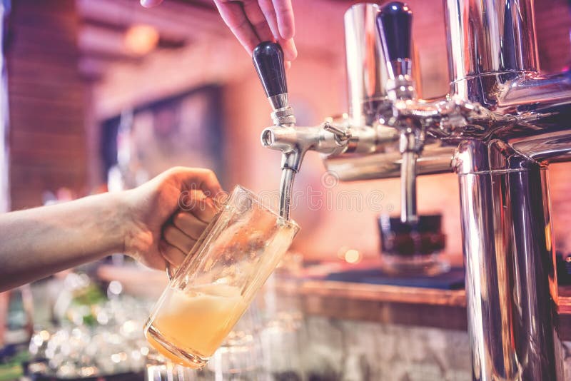 Χέρι μπάρμαν στη βρύση μπύρας που χύνει μια μπύρα ξανθού γερμανικού ζύού έλξης στο εστιατόριο, το μπαρ ή το bistro