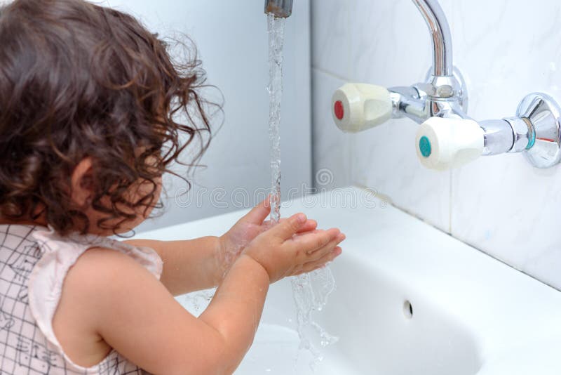 Little girl in bathroom washing hands.Curly sweet baby play in water.Healthy, Child`s Hygiene concept. Little girl in bathroom washing hands.Curly sweet baby play in water.Healthy, Child`s Hygiene concept.