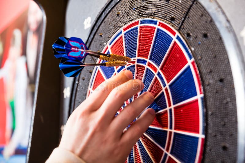 Χέρι προσώπου που αφαιρεί τα βέλη από το dartboard στοκ εικόνα Χέρι προσώπου που αφαιρεί τα βέλη από το dartboard στοκ εικόνα