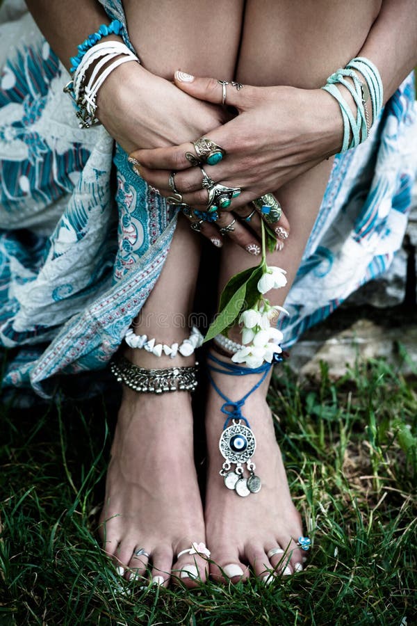 Χέρια γυναικών λεπτομερειών μόδας Boho και γυμνά πόδια στη χλόη με το μέρος στοκ εικόνες με δικαίωμα ελεύθερης χρήσης