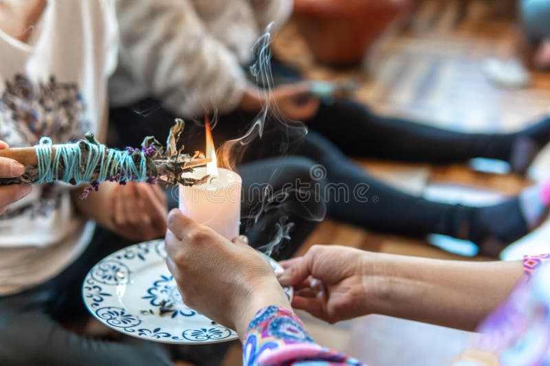 χέρια θηλυκού σαμάνου με ένα κερί που ανάβει ένα δέμα κανέλας σε μια τελετή επούλωσης στοκ φωτογραφίες