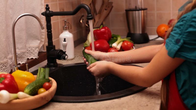 Χέρια νέων κοριτσιών που πλένουν ένα αγγούρι