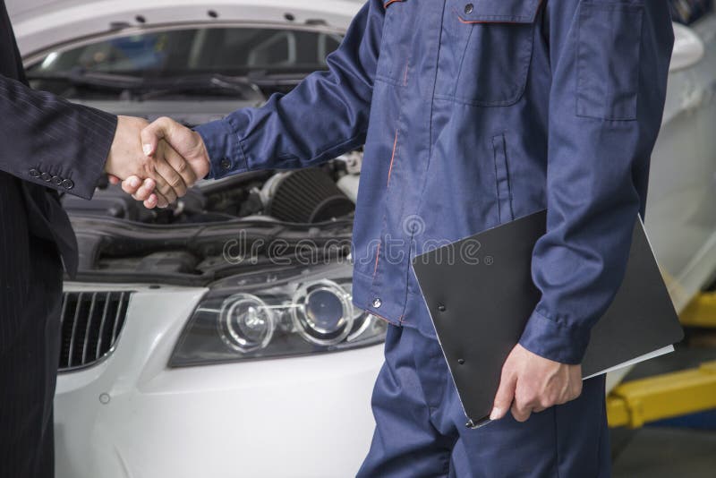 Businessman shaking hands with Mechanic in Auto Repair Shop. Businessman shaking hands with Mechanic in Auto Repair Shop