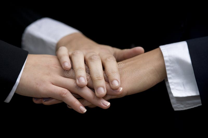 In a gesture of team work three young multi-ethnic business woman join hands. In a gesture of team work three young multi-ethnic business woman join hands.