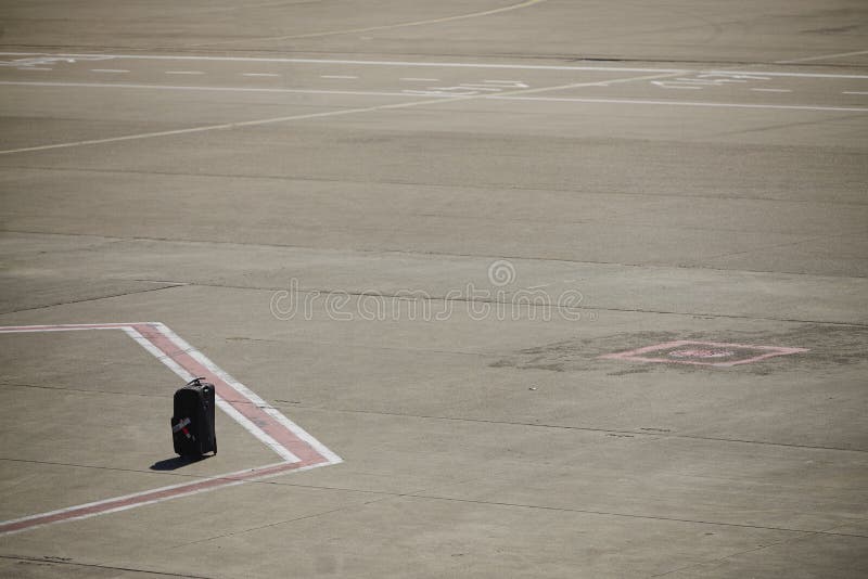 Single piece of left luggage on the runway tarmac at an airport, vacation concept. Single piece of left luggage on the runway tarmac at an airport, vacation concept.