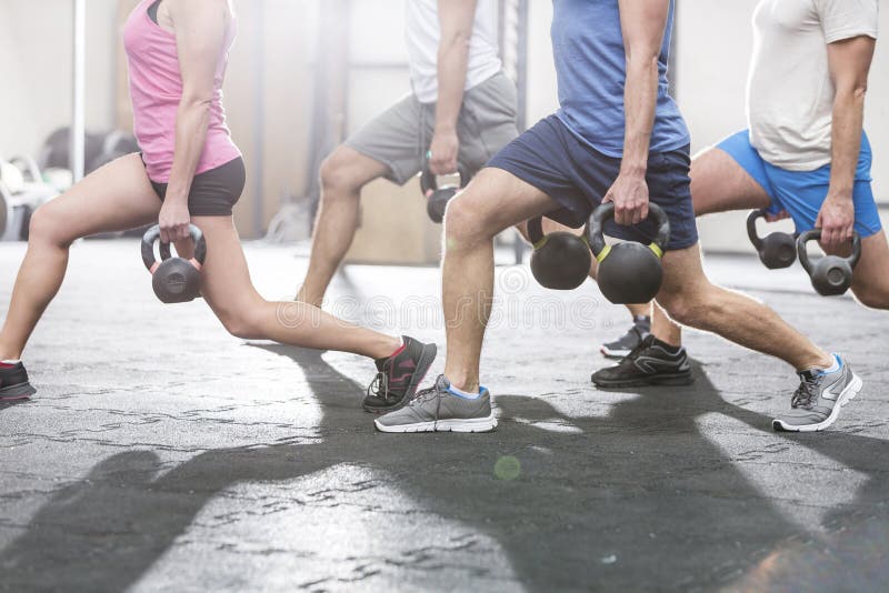 Low section of people lifting kettlebells at crossfit gym. Low section of people lifting kettlebells at crossfit gym