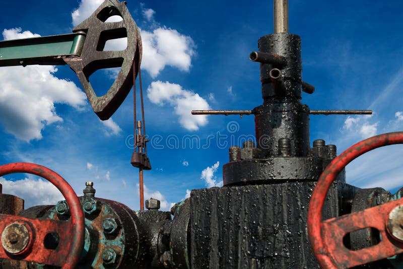 Low angle shot of a oil well pump against blue sky. Oil and gas industry. Cloudy blue sky. Low angle shot of a oil well pump against blue sky. Oil and gas industry. Cloudy blue sky