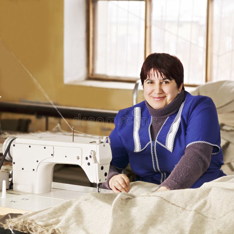 Χαμογελώντας seamstress μπλε smock στοκ φωτογραφία με δικαίωμα ελεύθερης χρήσης Χαμογελώντας seamstress μπλε smock στοκ φωτογραφία με δικαίωμα ελεύθερης χρήσης