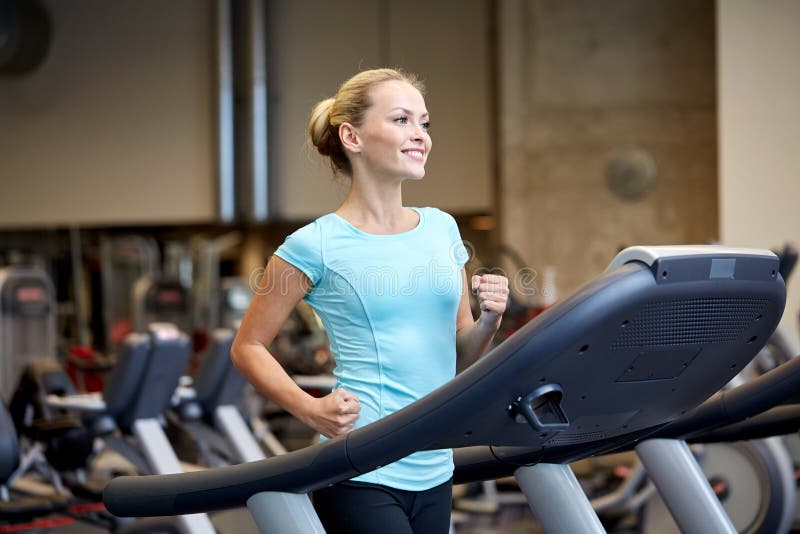 Χαμογελώντας γυναίκα που ασκεί treadmill στη γυμναστική στοκ εικόνες με δικαίωμα ελεύθερης χρήσης