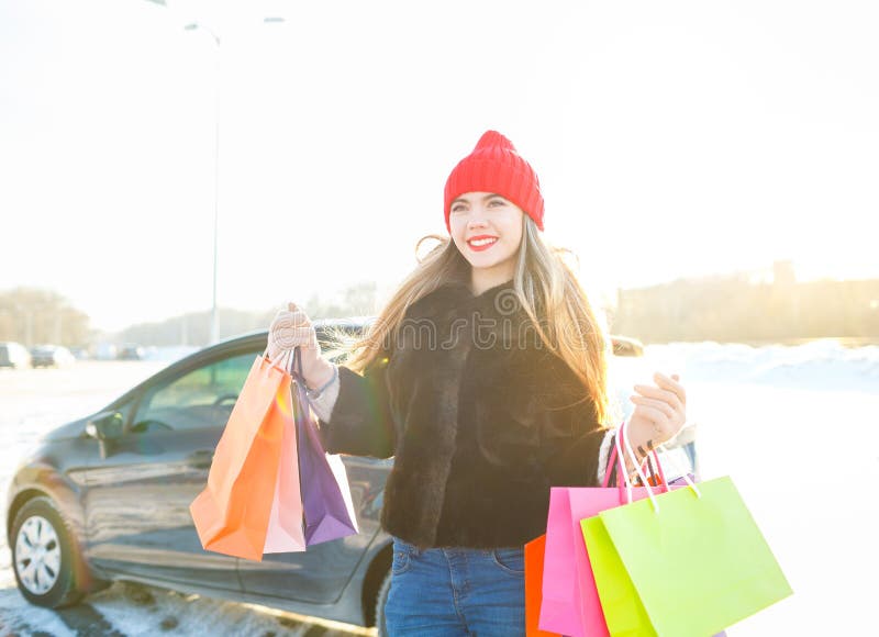 Χαμογελώντας καυκάσια γυναίκα που κρατά την τσάντα αγορών της κοντά στο αυτοκίνητο
