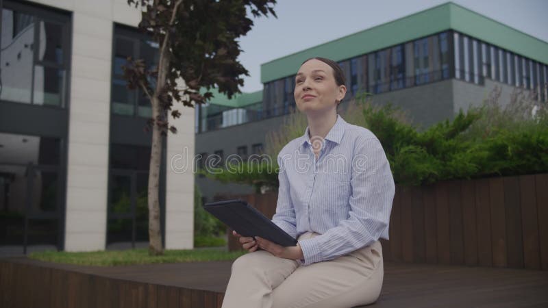 Χαμογελαστή Γυναίκα Που Κάθεται Έξω Από Το Κτίριο Του Γραφείου Χαιρετώντας Περαστικούς Συναδέλφους φιλμ μικρού μήκους