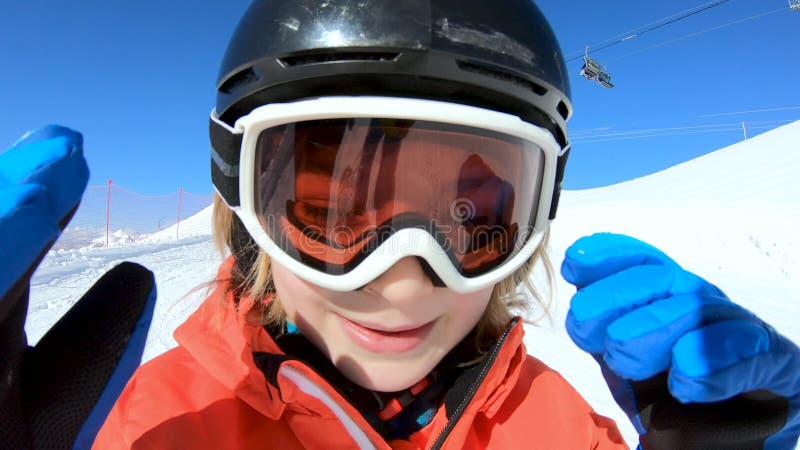 χαμογελαστό παιδί σκι και χέρι που χαιρετά στο χιόνι