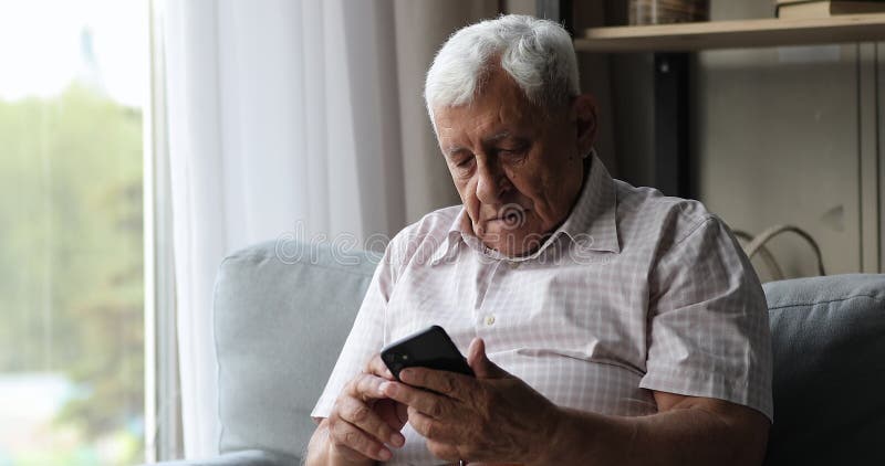 χαμογελαστός μεσήλικας συνταξιούχος πληρώνει online μέσω κινητού τηλεφώνου