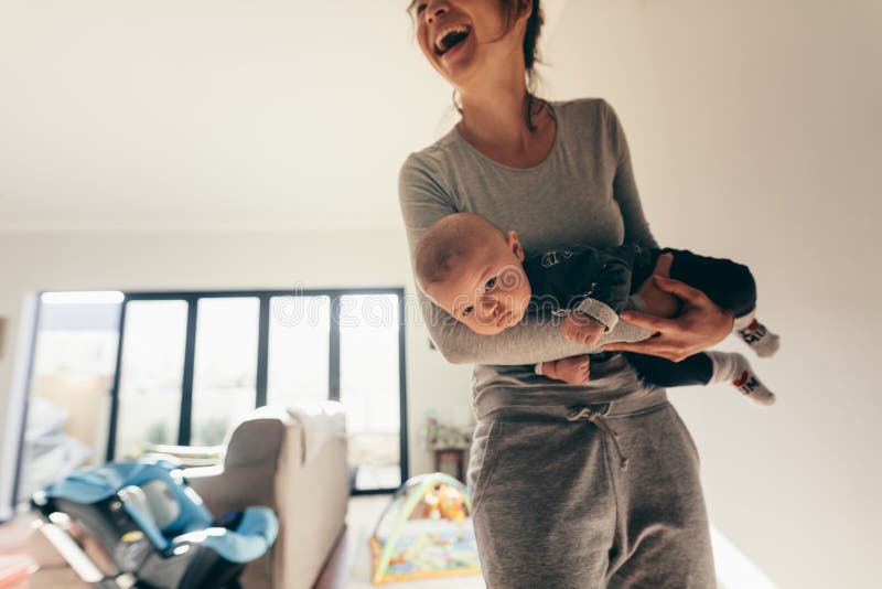 Χαμογελώντας γυναίκα που στέκεται στο δωμάτιο με το μωρό της
