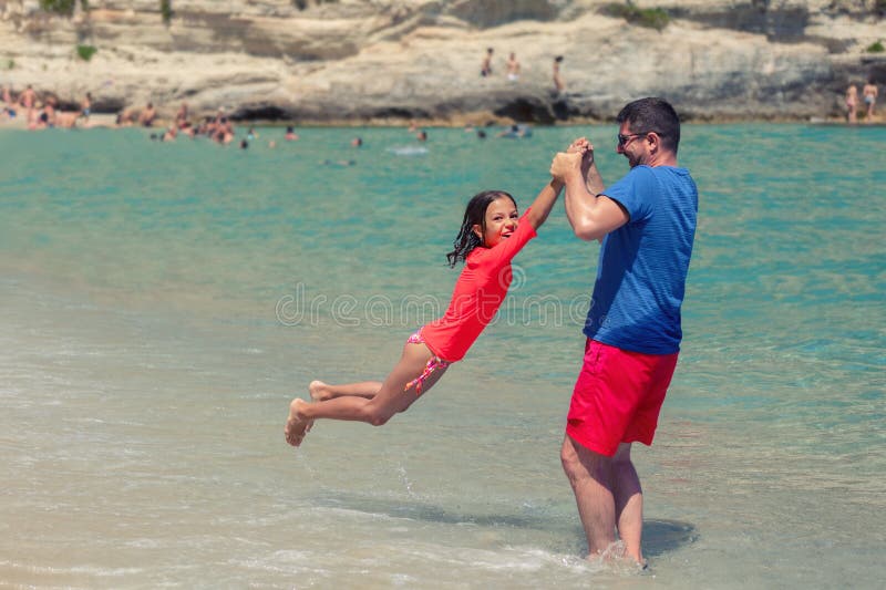 Χαμογελώντας παιχνίδι πατέρων και κορών μαζί στην παραλία, τον ευτυχή μπαμπά και το χαριτωμένο παιχνίδι μικρών κοριτσιών στην παρ στοκ εικόνες Χαμογελώντας παιχνίδι πατέρων και κορών μαζί στην παραλία, τον ευτυχή μπαμπά και το χαριτωμένο παιχνίδι μικρών κοριτσιών στην παρ στοκ εικόνες