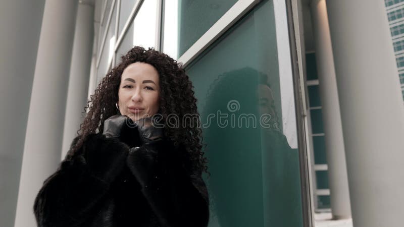 χαριτωμένη μελαχρινή μελαχρινή κοιτάζει την κάμερα σε εξωτερικό περίπατο στην πόλη το χειμώνα