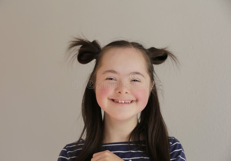 Cute smiling down syndrome girl on the grey background. Cute smiling down syndrome girl on the grey background.