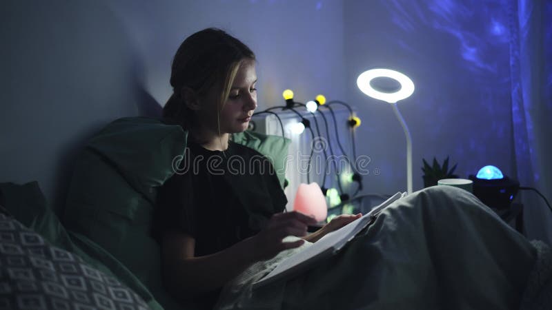 Χαριτωμένο κοριτσάκι διαβάζει βιβλίο στο κρεβάτι πριν κοιμηθεί απόθεμα βίντεο