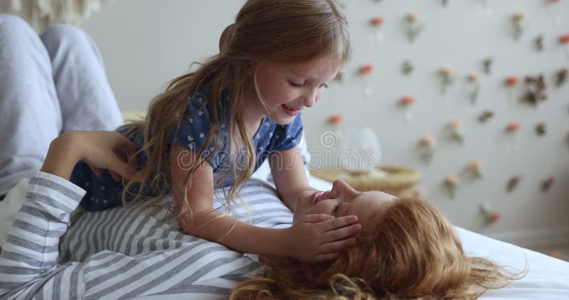 χαριτωμένο κοριτσάκι που αγαπά αναπαύεται στην ευτυχισμένη νεαρή μαμά