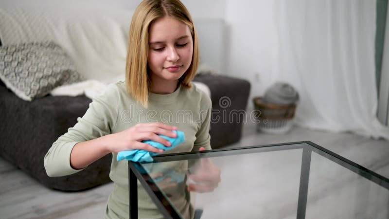 Χαριτωμένο κοριτσάκι που σκουπίζει ένα γυάλινο τραπέζι με πανί απόθεμα βίντεο