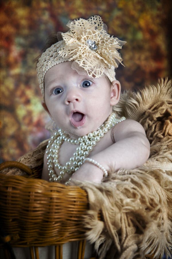 Beautiful little blue-eyed baby girl with bows, pearls and fun expression. Beautiful little blue-eyed baby girl with bows, pearls and fun expression