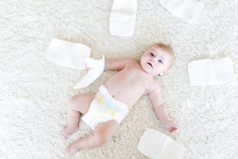 Cute adorable newborn baby of 3 moths with diapers. Hapy tiny little girl or boy looking at the camera. Dry and healthy body and skin for children concept. Baby nursery. Cute adorable newborn baby of 3 moths with diapers. Hapy tiny little girl or boy looking at the camera. Dry and healthy body and skin for children concept. Baby nursery