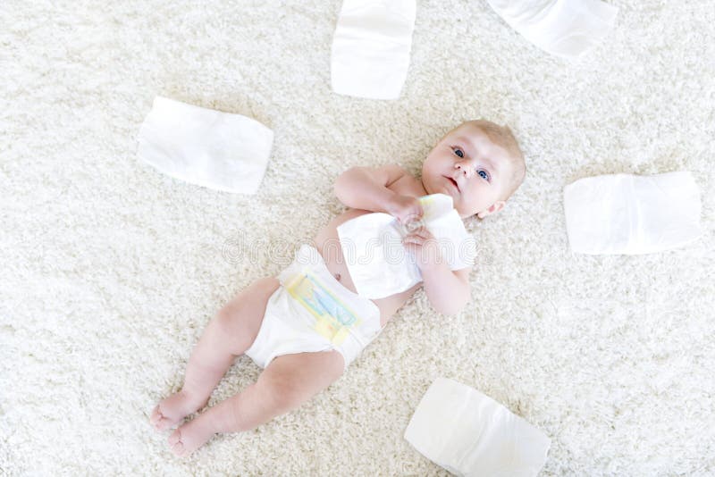 Cute adorable newborn baby of 3 moths with diapers. Hapy tiny little girl or boy looking at the camera. Dry and healthy body and skin for children concept. Baby nursery. Cute adorable newborn baby of 3 moths with diapers. Hapy tiny little girl or boy looking at the camera. Dry and healthy body and skin for children concept. Baby nursery