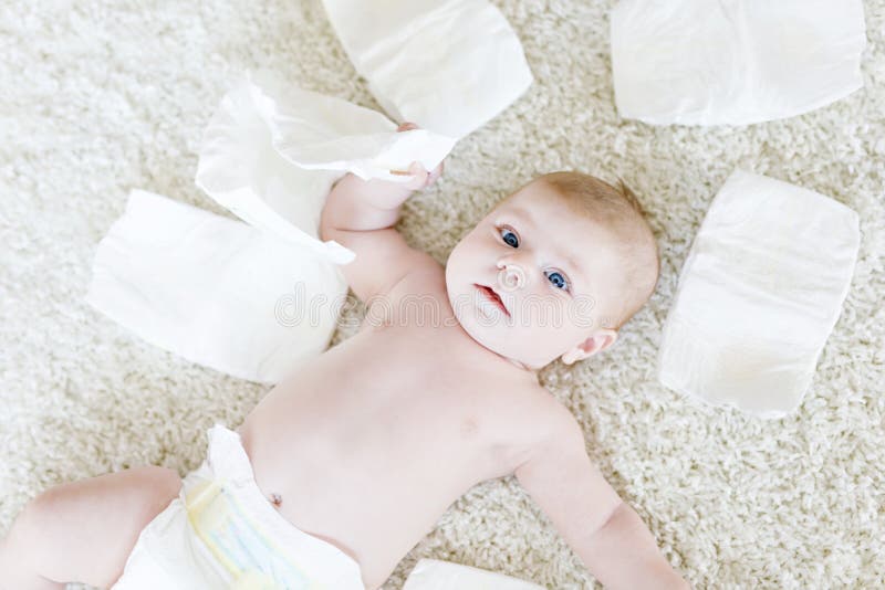 Cute adorable newborn baby of 3 moths with diapers. Hapy tiny little girl or boy looking at the camera. Dry and healthy body and skin for children concept. Baby nursery. Cute adorable newborn baby of 3 moths with diapers. Hapy tiny little girl or boy looking at the camera. Dry and healthy body and skin for children concept. Baby nursery