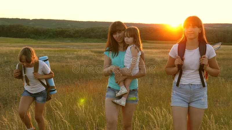 Χαρούμενα κορίτσια ταξιδεύουν στο πεδίο με το φως του ήλιου Κορίτσι-πεζοπορία Συνοικίες σε λιβάδια Κορίτσια ταξιδεύουν με σακίδια