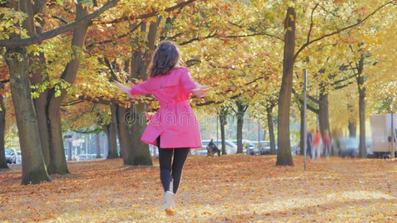 χαρούμενη γυναίκα από τον καύκασο που περπατάει στο πάρκο του φθινοπώρου