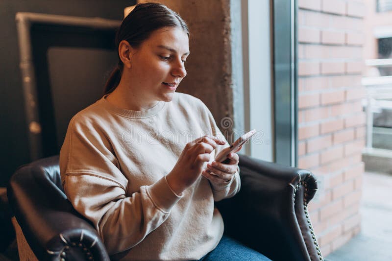 30s woman laughing holding smartphone, enjoying doing online ecommerce shopping in mobile apps or watching video at home. 30s woman laughing holding smartphone, enjoying doing online ecommerce shopping in mobile apps or watching video at home