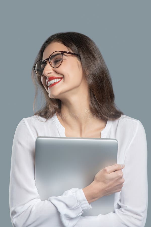 χαρούμενη νεαρή γυναίκα που πιέζει φορητό υπολογιστή σε αυτήν